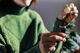 Woman holding small brown bottle with dropper.