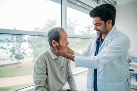doctor inspecting man's neck