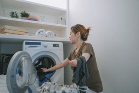 Asian woman with differently-abled arm doing laundry at home