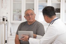 Doctor using digital tablet to talk to senior man