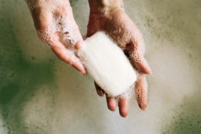 Person holding sudsy bar of soap over water