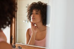 Young woman looking at her complexion in the mirror