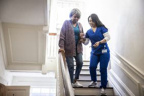 nurse helping woman with myasthenia gravis down a staircase