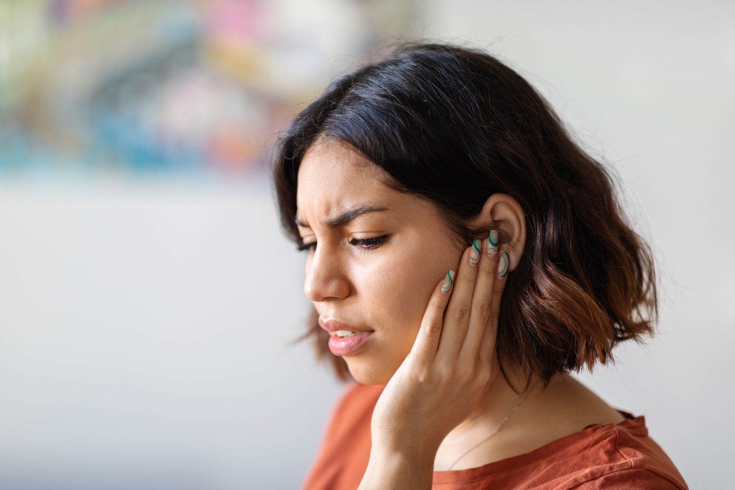 young woman with tinnitus holding her ear due to discomfort