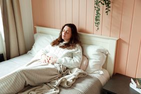 young woman with enteritis laying in bed with stomach pain