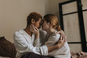 two females hugging in bed