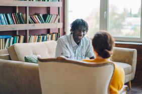 man sitting on the cough in a therapist's office talking to therapist sitting in a chair