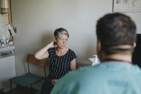 woman experiencing myasthenia gravis symptoms including ptosis and neck pain