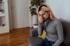 Woman sitting on sofa touching her nose having sinus problems