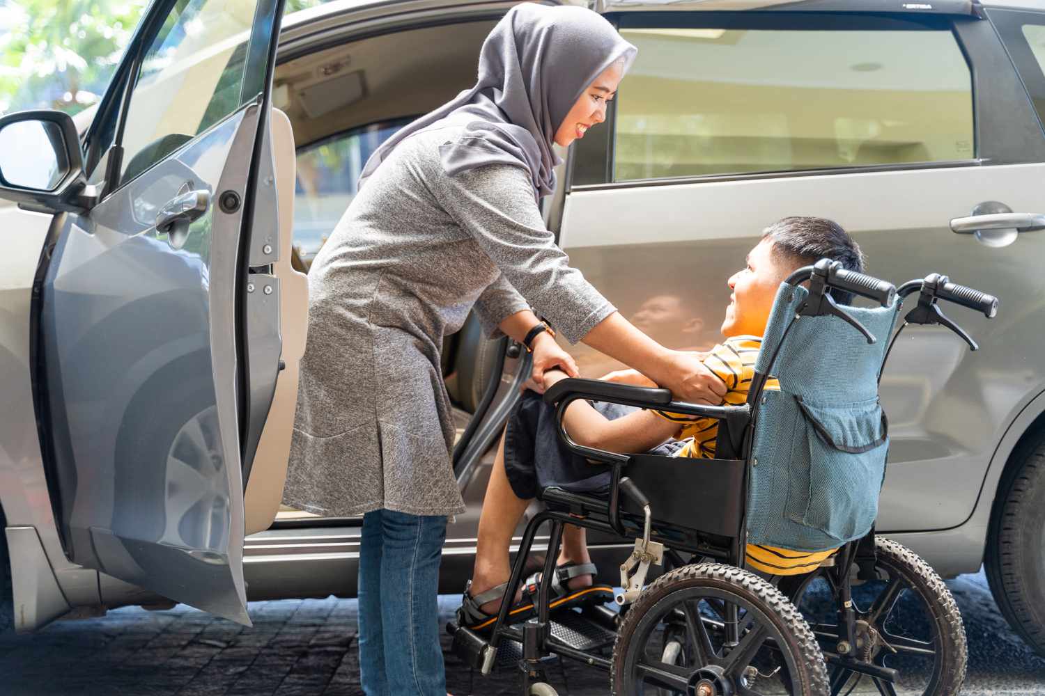 a woman helping a boy with muscular dystrophy who is in a wheelchair