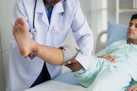 orthopedist assisting man with leg pain