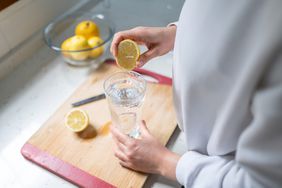 person squeezing lemon into carbonated water
