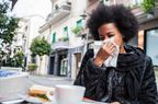 Woman sneezing due to cold during a break in a cafe using an handkerchief