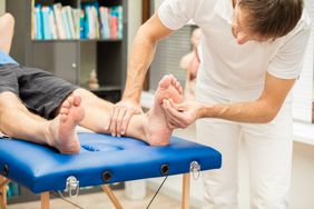 A doctor, testing the sensibility of a patient`s foot. This test is often used for checking neuropathy of diabetic patients.