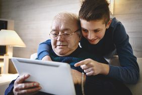 Grandfather And Grandson Using Digital Tablet Together