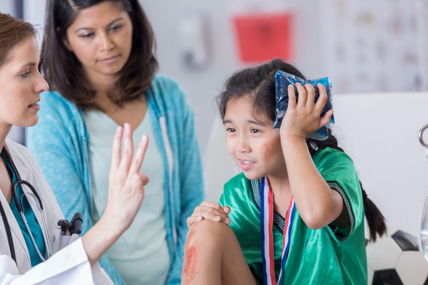 ER doctor examines young injured soccer player with concussion