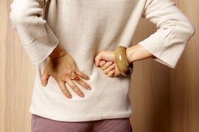 Woman with lower backache due to sciatica, massaging her back.
