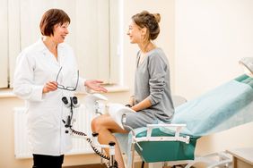 female sitting on gynecologist table talking to doctor