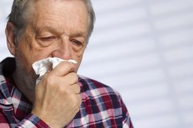 older man who is coughing up blood into a tissue
