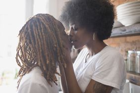 Two females kissing in a kitchen