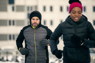 man and woman winter jogging on city street