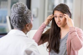 young woman explaining her headache to female doctor 