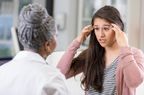 young woman explaining her headache to female doctor 