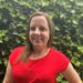 Woman wearing a red shirt standing in front of green ivy