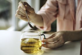 Woman stirring a clear glass mug of tea
