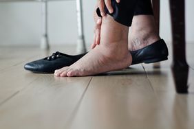 Close up of an older woman's swollen ankles; she is touching her ankle as she puts on her shoes