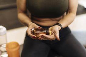 Woman wearing leggings and sports top taking supplement after a workout