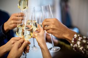 Close-up of hands toasting champagne flutes during dinner party at home