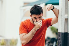 A man holds his hand to his mouth