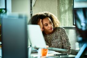 Person at computer, looking off in the distance, apathetic