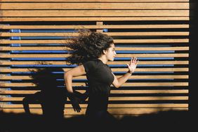 Person sprinting in front of wood paneling.