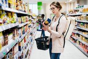 Person reading food label on product in supermarket