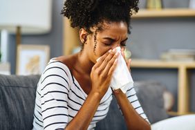Woman coughing into a tissue at home.