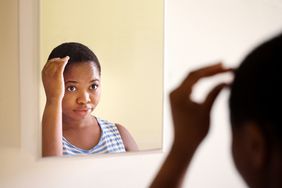 Person checking their scalp in the bathroom mirror.