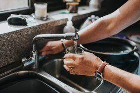 person filling a glass with tap water