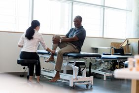 man speaks with doctor about leg pain