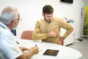 A man shows a doctor the pain in his upper left abdomen 