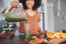 Woman pouring smoothie from a blender in her kitchen