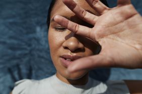 A woman blocks her eyes from bright light.