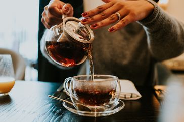 hand pouring cup of tea