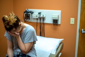 Person has their head in their hands, seemingly crying at the doctor's office.