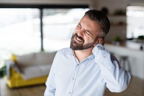 A man holds the back of his head in pain