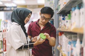 Two people looking at a supplement in a grocery store