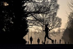 A jogger runs in Preston Park, in Brighton, south of England, at sunrise