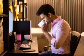 Stressed young Indian businessman getting sick while working overtime at home late at night
