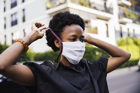 Person putting on face mask outside.